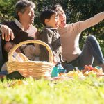 A happy family captures a selfie during a sunny picnic in a Portuguese park.