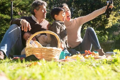 A happy family captures a selfie during a sunny picnic in a Portuguese park.