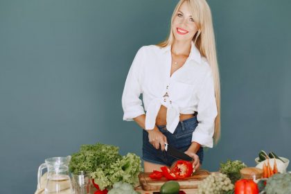 A smiling blonde woman chops vegetables, promoting healthy eating and lifestyle.